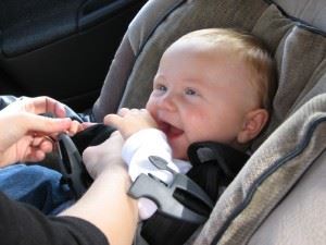 Baby being buckled in rear facing car seat