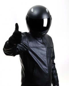 Motorcycle rider wearing black safety jacket and helmet holding his thumb up